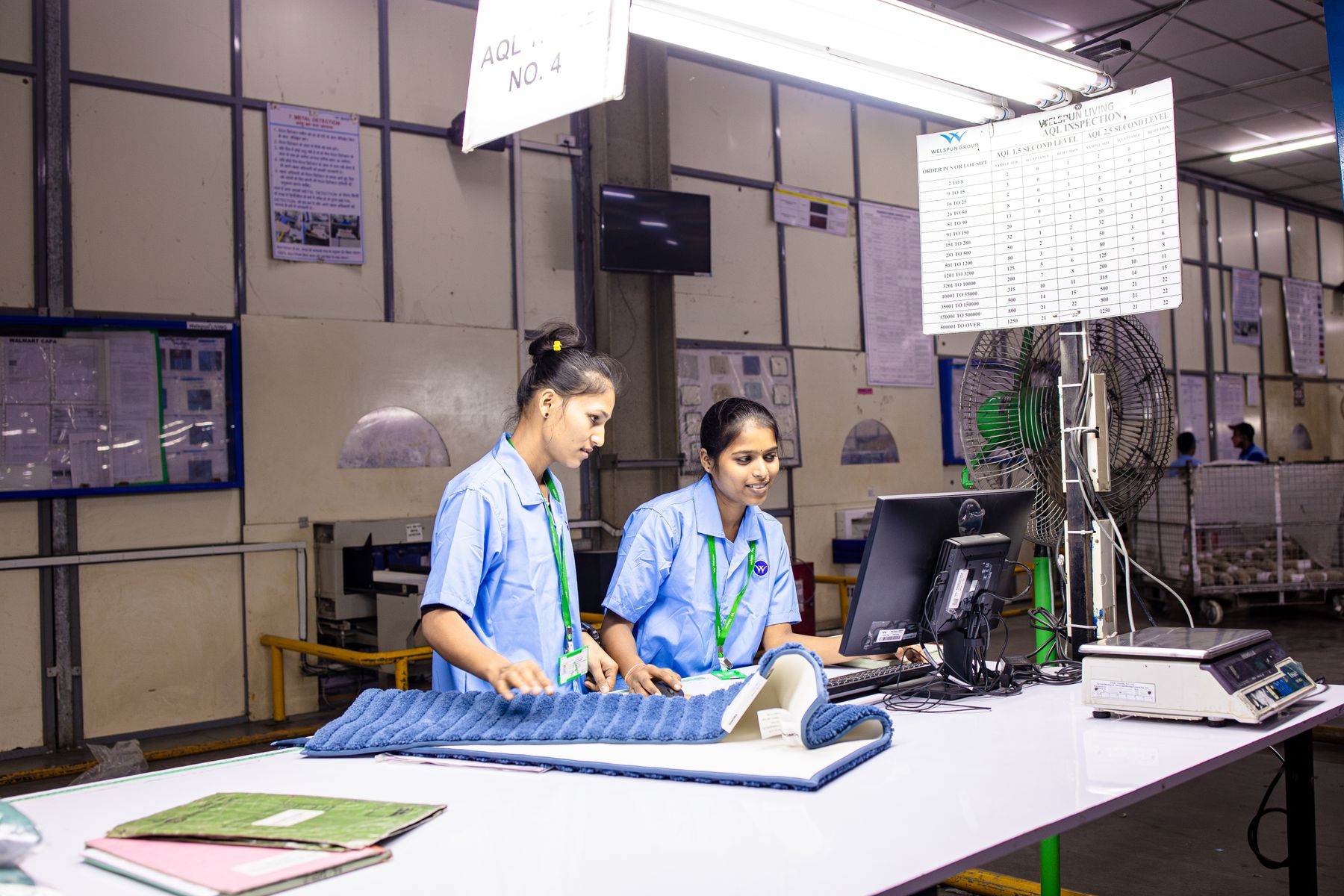Workers inspecting fabric at a factory inspection table